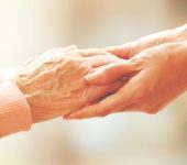 Hands of a young woman holding elderly person's hands.