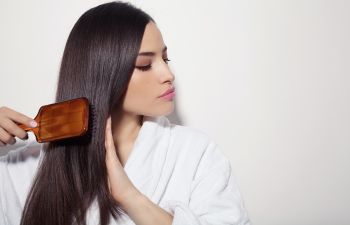 A young brunette woman brushing her long hair.