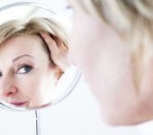 Mature woman looking at her face in a mirror and considering facial Anti-Aging Treatments in Beverly Hills CA