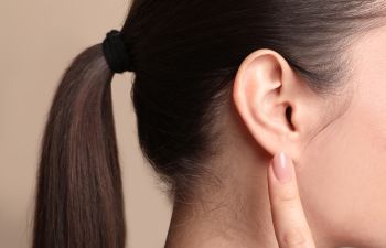 Young woman pointing at her ear.