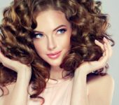 beautiful woman touches her curly hair and smiles mysteriously