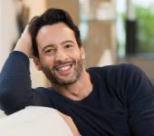 smiling middle aged man sitting on couch