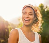 joyful girl with headband in hair laughing against the trees and sunset