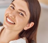 Attractive woman visiting dental clinic. Happy young woman sitting in dental chair at dentist office