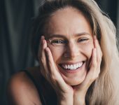 No filter studio photo of pretty shiny woman wear lingerie arms cheeks enjoying self acceptance isolated khaki cloth background